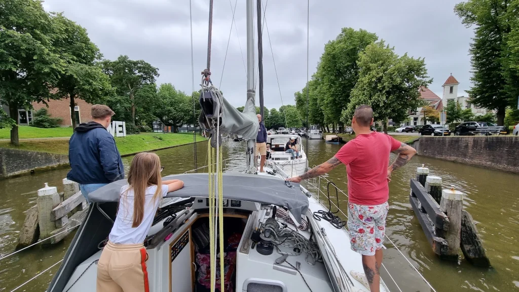 Vanaf het voordek: de Eowyn wordt door een andere zeilboot op sleeptouw dwars door de grachten van Leeuwarden getrokken, familie aan dek.