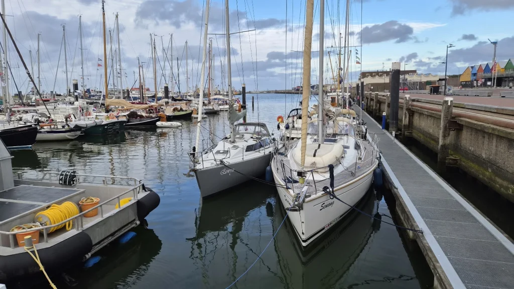 In de haven van Lauwersoog liggen twee Feelings naast elkaar langs een steiger: de grijze Eowyn en de grotere witte Senang met teakdek, voor een kade met gekleurde huisjes en een haven vol masten.